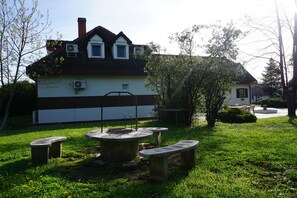 A house with a sloped roof, two air conditioning units, and a small porch with a bench. - Május 1 Vendégház - Torony (Torony)