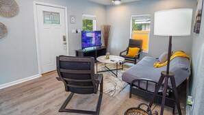 A modern living room with a ceiling fan, a flat-screen TV, a sofa, a chair, and a lamp. - Charming Fenced 3BR/1BA Close to Vibrant Downtown (San Antonio)