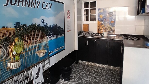 Une cuisine avec un mur recouvert de carreaux, un plan de travail noir et une fenêtre.