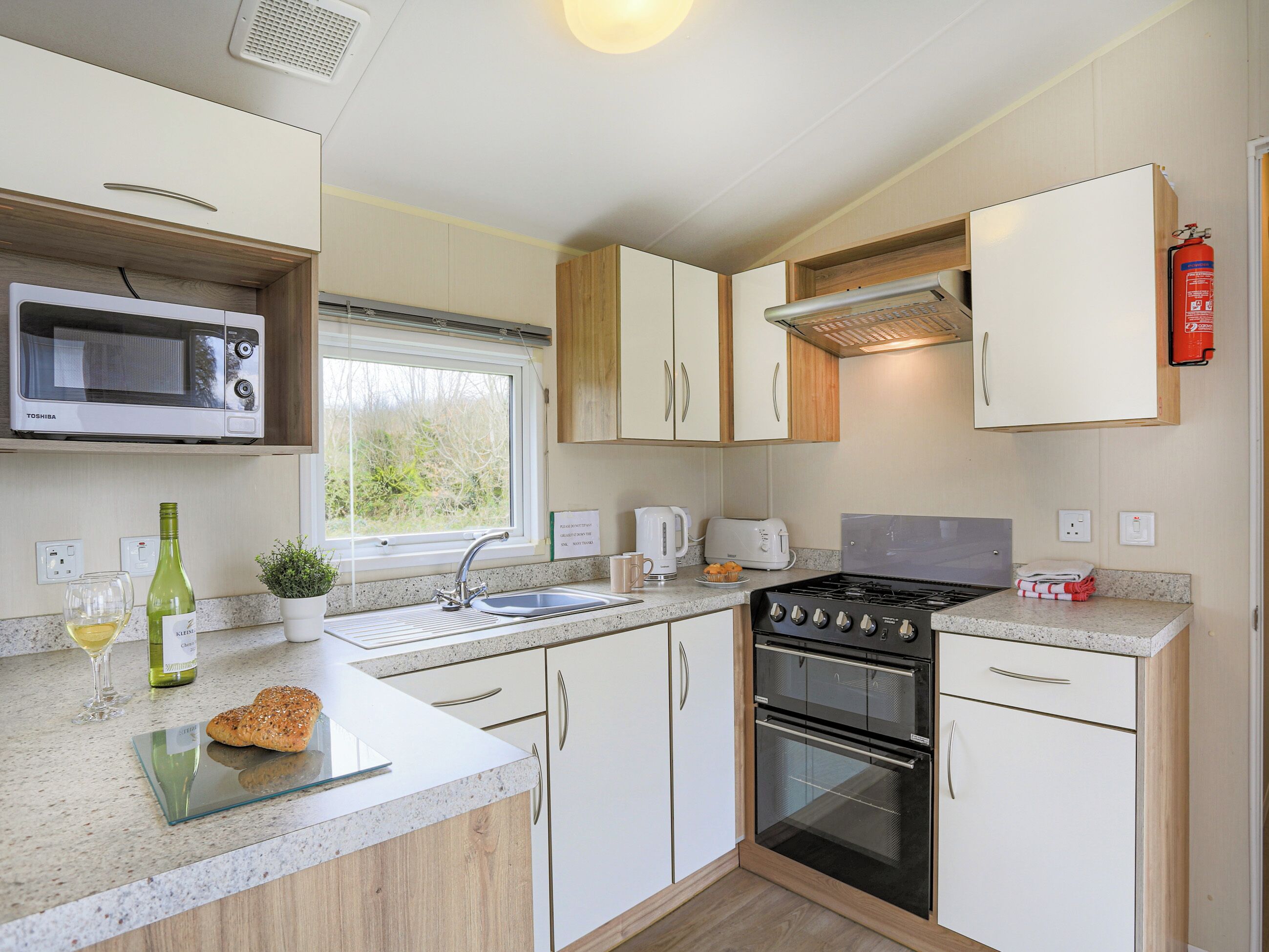 A modern kitchen with a microwave, stove, sink, and wooden cabinets.