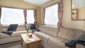 A cozy living room with a sofa, a wooden coffee table, and a vase of flowers.