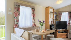 A cozy living room with a sofa, a wooden table, a television, and a bookshelf.