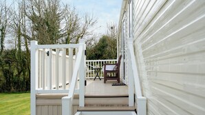 A wooden deck with a white railing leading to a white building.