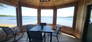 A wooden deck with a table and chairs facing a lake. - Chalet Le 48 (Mandeville)