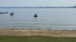 A calm body of water with boats and a grassy shoreline. - Chalet Le 48 (Mandeville)