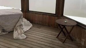 A room with a bed, a small table, and large windows overlooking a body of water. - Chalet Le 48 (Mandeville)