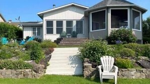 A two-story house with a covered porch and a landscaped garden. - Chalet Le 48 (Mandeville)