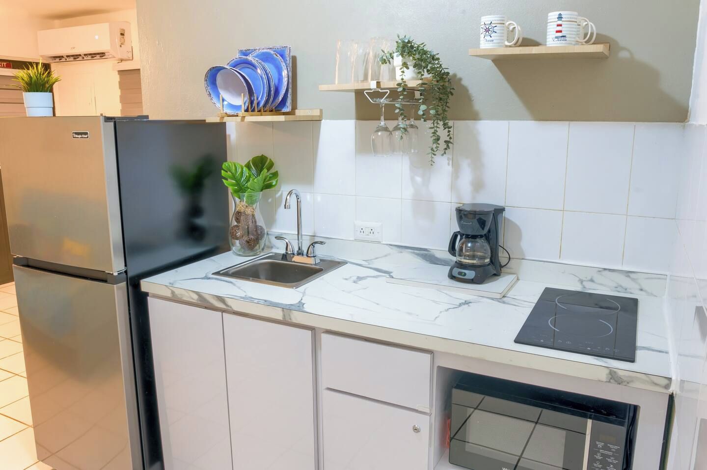 Una cocina equipada con lavavajillas, fregadero, cafetera y microondas.