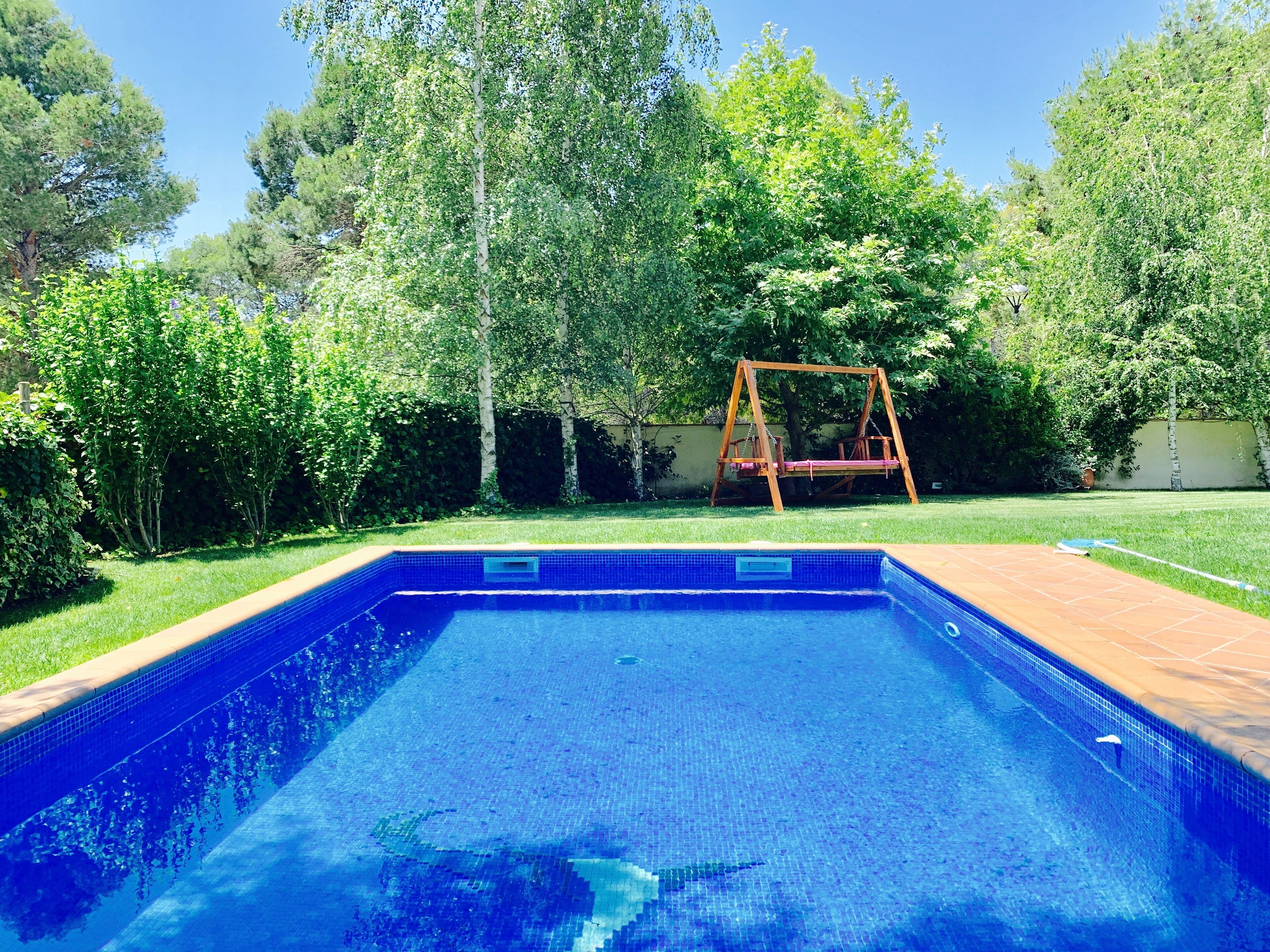 A rectangular swimming pool with a wooden deck surrounding it.
