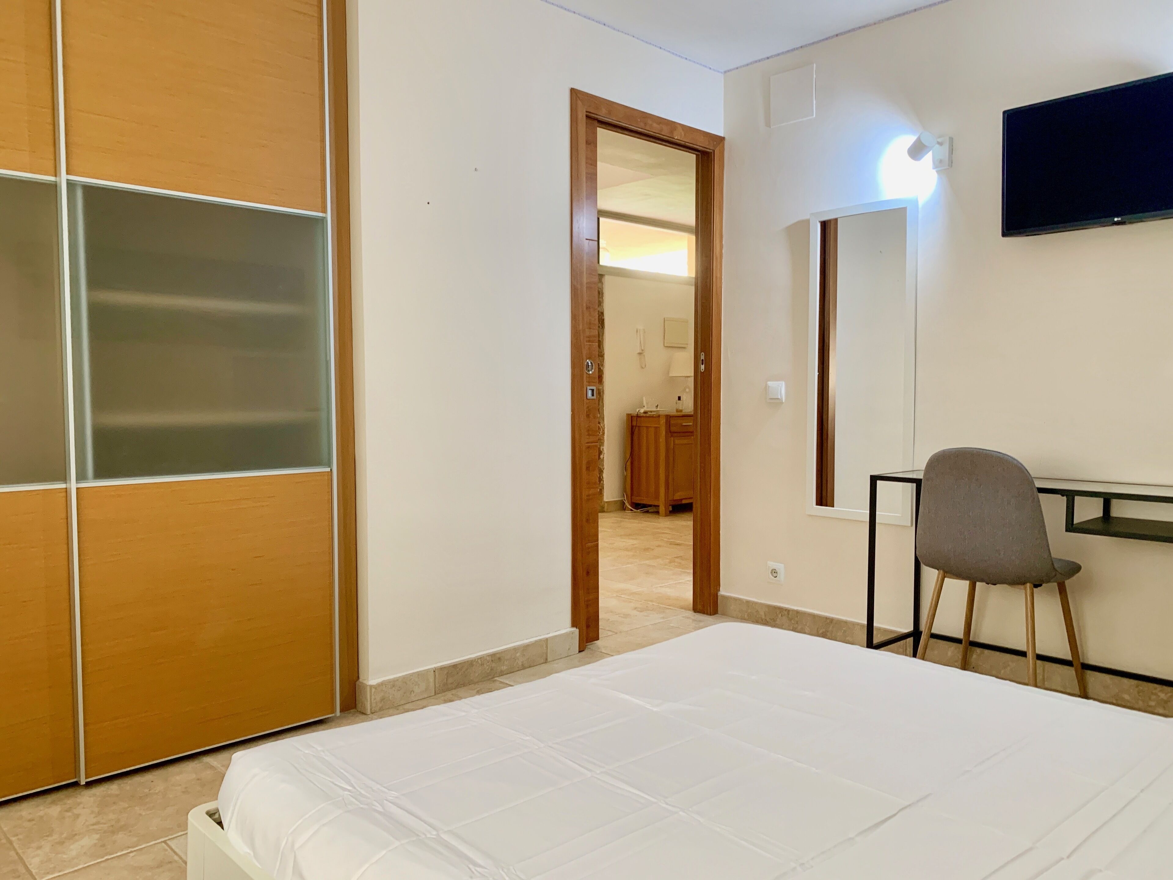 A hotel room with a bed, a desk, a chair, and a TV.