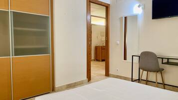 A hotel room with a bed, a desk, a chair, and a TV.