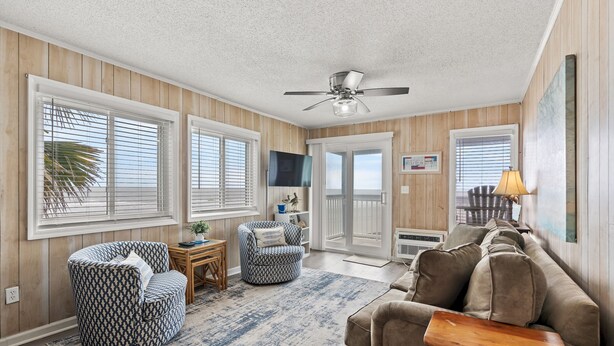 A living room with a patterned ottoman, a brown sofa, and a ceiling fan. - Oceanfront View @ A Place at the Beach 3 1I (Myrtle Beach)
