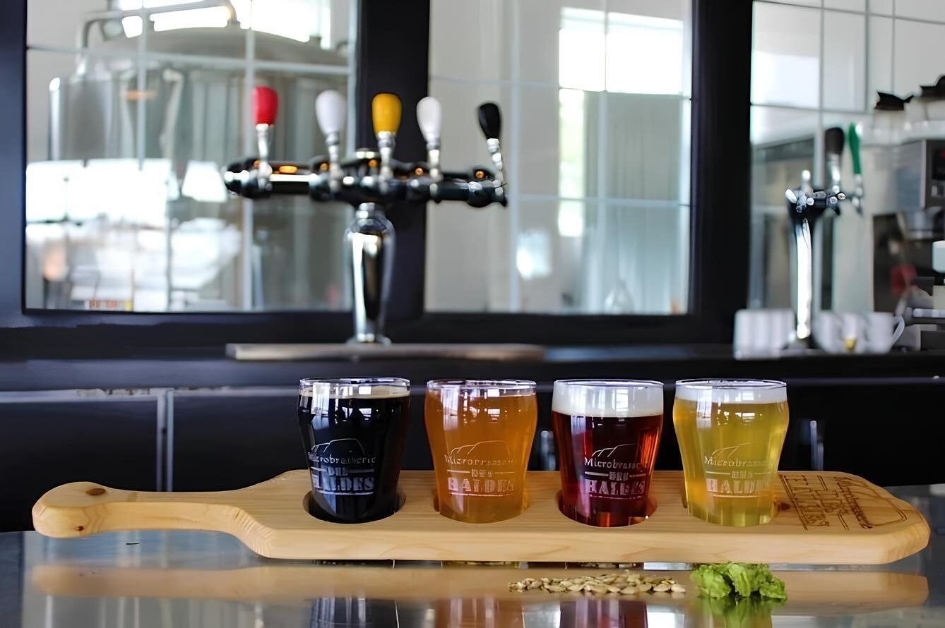 Een bar met een bierkraan en vier glazen bier op een houten plank.