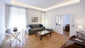 A modern living room with a sofa, coffee table, and clear glass dining table. - Three Steps from Spanish Steps (Roma)