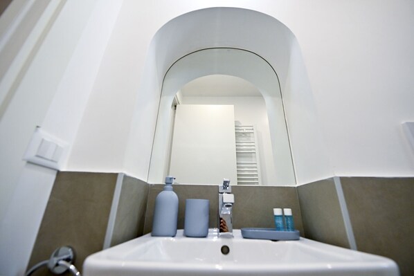 A bathroom with a white sink, a mirror, and a towel rack. - Three Steps from Spanish Steps (Roma)