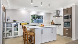 Una cocina moderna con armarios blancos, una isla central, horno empotrado y ventana con vistas a zonas verdes.