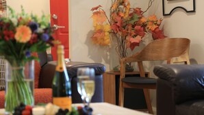 Ein Essbereich mit Tisch für zwei Personen, mit einer Champagnerflasche, einem Glas und einer Vase mit Herbstlaub.