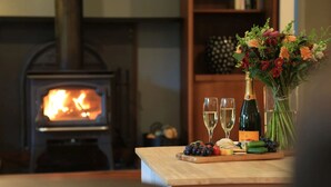 Ein gemütliches Zimmer mit Kaminofen, einem Tisch mit Champagner, Gläsern und einer Obstplatte.