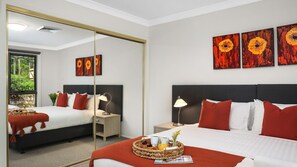 Habitación de hotel con dos camas, un espejo grande, obras de arte en la pared y vistas al exterior.