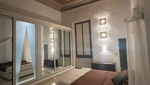 A bedroom with a large bed, a wardrobe with mirrors, and a ceiling with decorative moldings. - Piazza santa croce, uffizzi, luxury apartment in historic building  (Firenze)