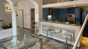 A modern kitchen with a glass bar and seating area, a washing machine in the background, and a staircase leading to an upper level. - Piazza santa croce, uffizzi, luxury apartment in historic building  (Firenze)