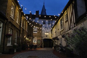 A narrow cobblestone street with buildings on either side, string lights overhead, and a sign indicating a hotel reception. - The Blue Boar - Maldon (Maldon)