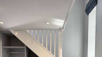 A staircase with dark carpeted steps leading to a landing with a white railing.