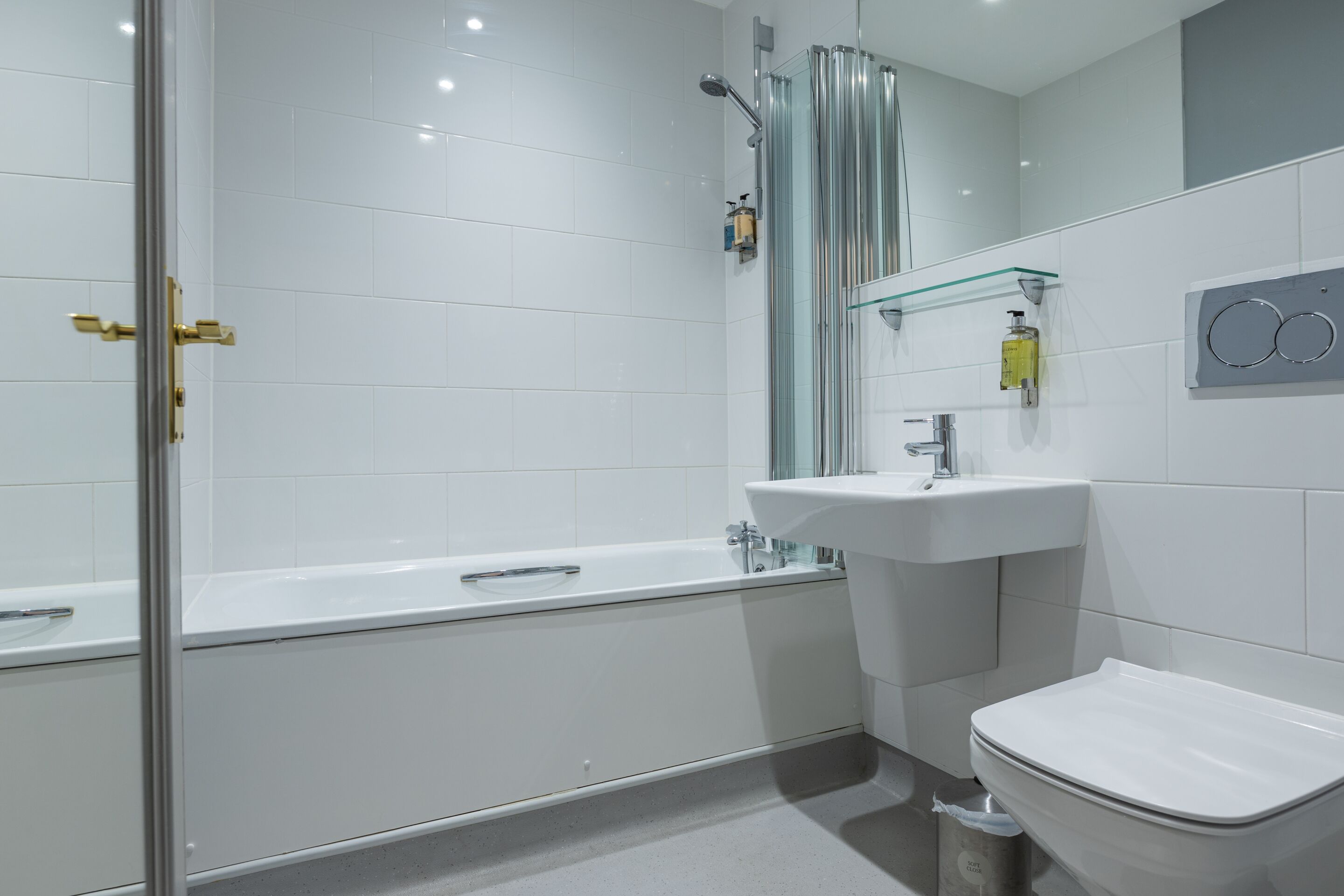 A modern bathroom with a glass-enclosed shower, a white bathtub, a sink, and a toilet.