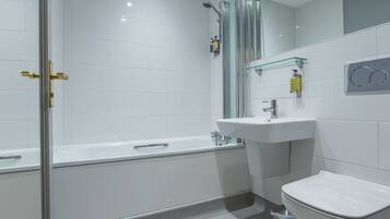 A modern bathroom with a glass-enclosed shower, a white bathtub, a sink, and a toilet.