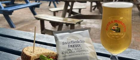Un montaje para picnic con un sándwich, ensalada y una jarra de cerveza sobre una mesa de madera.