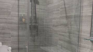 Un baño moderno con ducha acristalada, inodoro blanco y lavamanos pedestal.