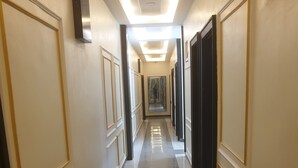 A long, narrow hallway with a polished floor and decorative wall paneling. - Downunder Suites (Abuja)