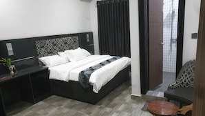 A modern hotel room with a neatly made bed, a small table, a chair, and a bathroom visible through an open door. - Downunder Suites (Abuja)