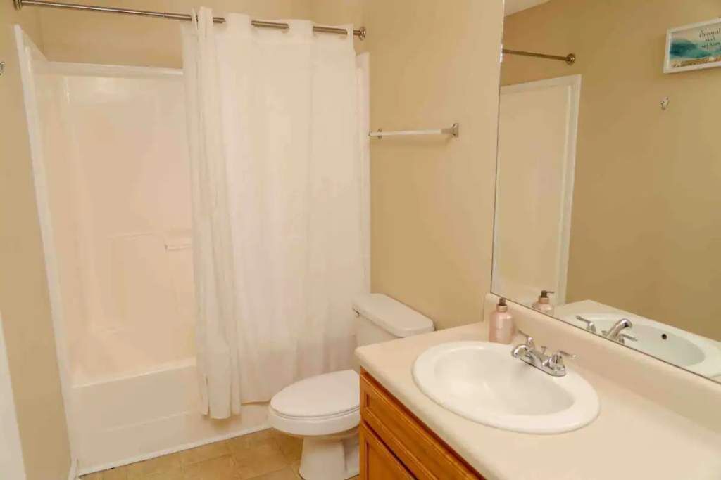 A bathroom with a bathtub, toilet, sink, and mirror.