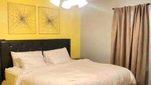Un dormitorio con una cama, un ventilador de techo y dos cuadros en la pared.