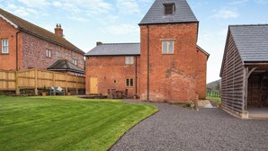 A brick building with a tower, a wooden fence, and a gravel path.