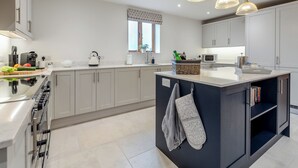 A modern kitchen with a central island, built-in appliances, and pendant lighting.