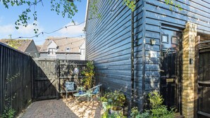 A backyard with a wooden fence, a brick patio, and potted plants. - Delightful recently completed Annexe close to Cambridge. (Cambridge)