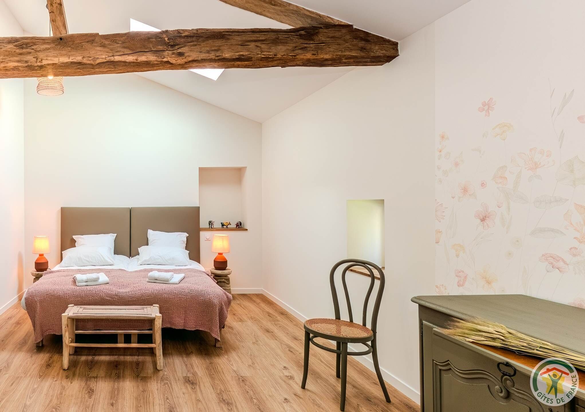 A bedroom with a wooden bed, a bench, a chair, and a dresser.