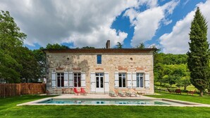A stone house with a swimming pool, surrounded by a well-maintained lawn and trees. - LA Maison DE Ninette (Castelculier)