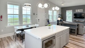 A modern kitchen with a large island, white cabinetry, and pendant lighting. - Beautiful Beach Views Sleeps 8 (Gulfport)
