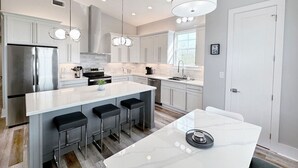 A modern kitchen with a large island, stainless steel appliances, and pendant lighting. - Beautiful Beach Views Sleeps 8 (Gulfport)