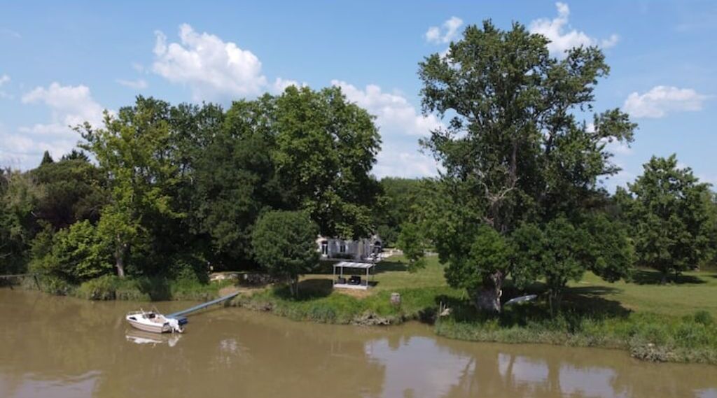 A riverside property with a boat dock, a covered outdoor seating area, and lush greenery.