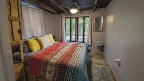 A bedroom with a bed, a window with curtains, a ceiling fan, and a small bedside table. - Nature Escape, Outdoor Cinema & River Adventure (Lares)