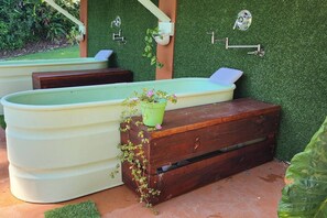 A pool area with a wooden bench and a green planter with flowers.