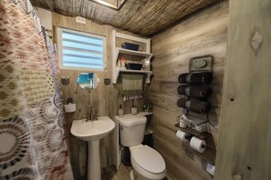 Ein kleines Badezimmer mit Holzvertäfelung, einem Waschbecken, einer Toilette und einem Handtuchhalter.