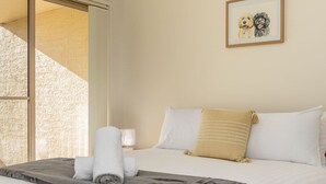 A hotel room with a bed, a window with a view, and a framed picture on the wall.
