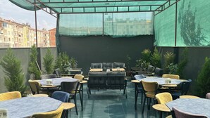 An outdoor seating area with tables and chairs, covered by a green canopy. - Vizyon Life Pansiyon (Elazig)