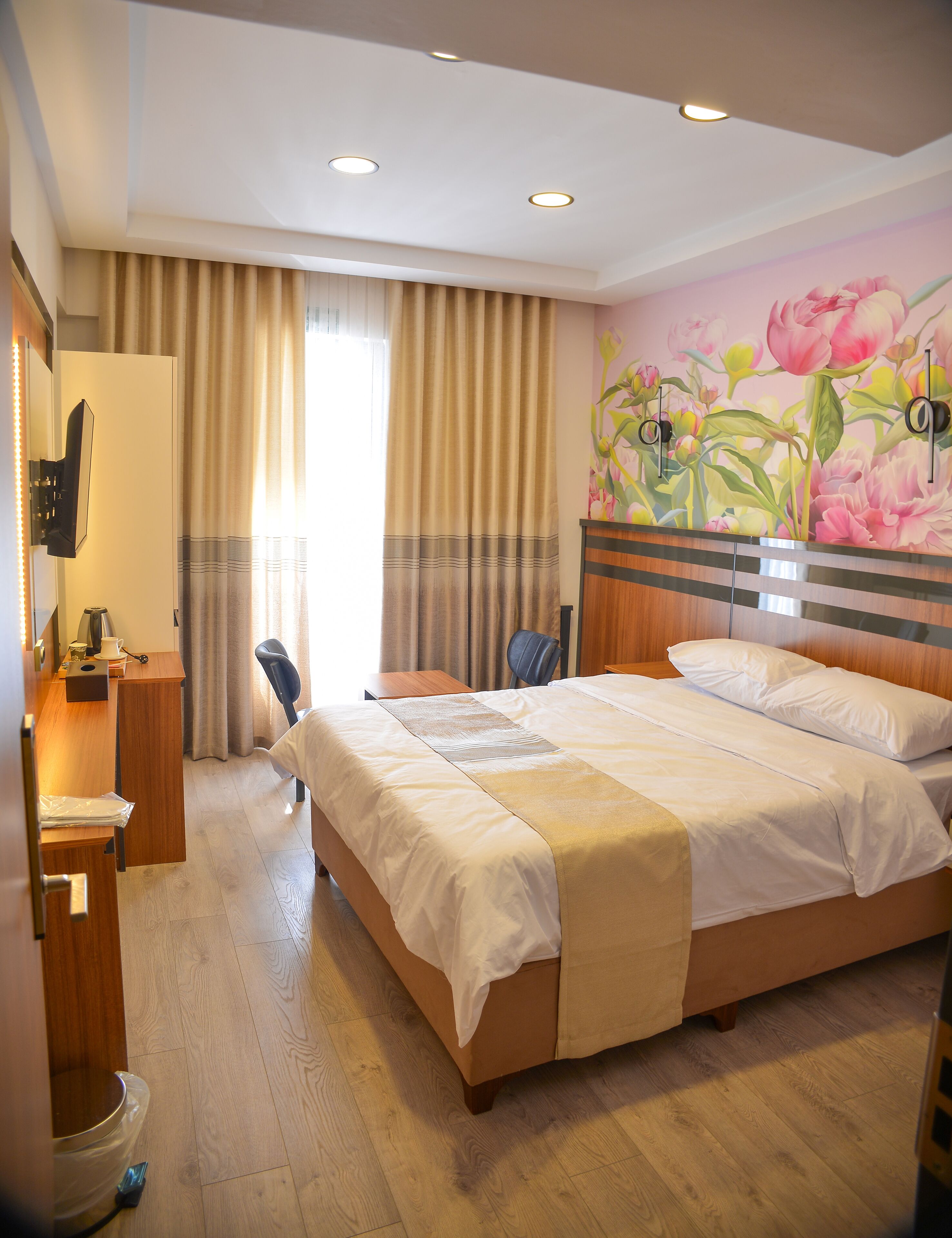 Habitación de hotel con una cama grande, un escritorio con silla, un armario de madera y un baño con inodoro.