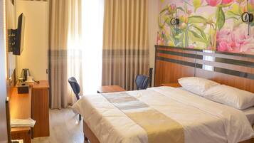 Habitación de hotel con una cama grande, un escritorio con silla, un armario de madera y un baño con inodoro.